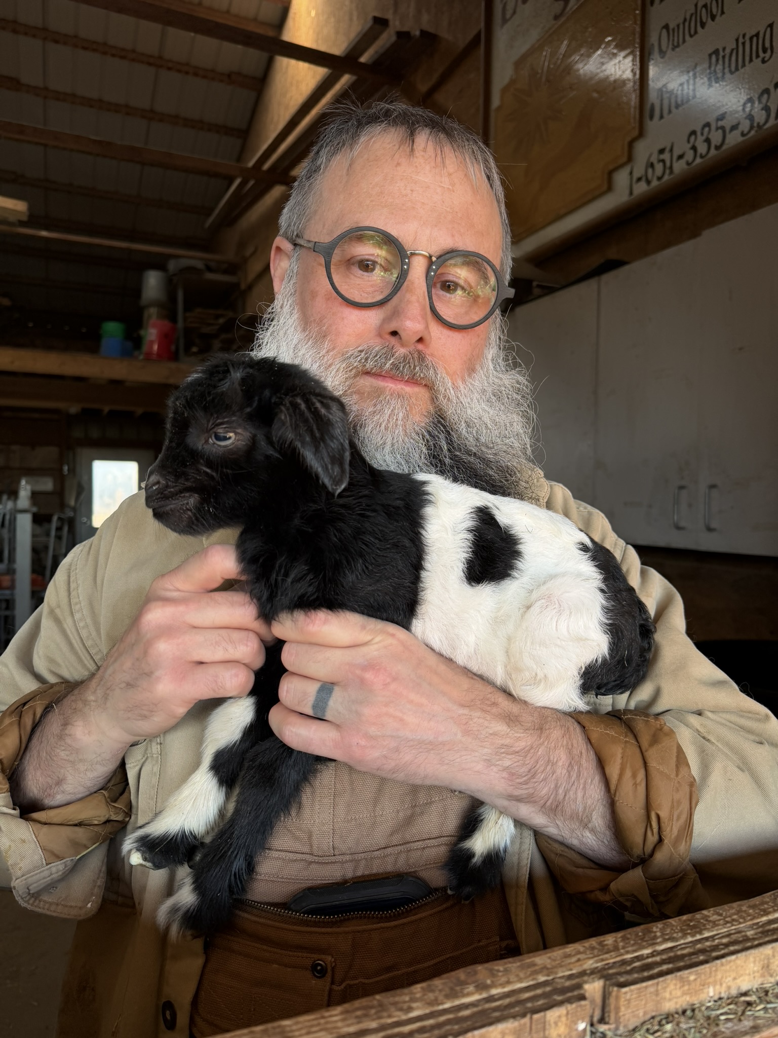 man holding newborn black and white goat